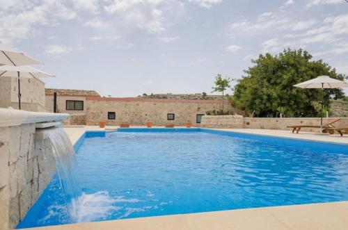 a large blue swimming pool with an umbrella at Villa Dolce Valle in Ragusa