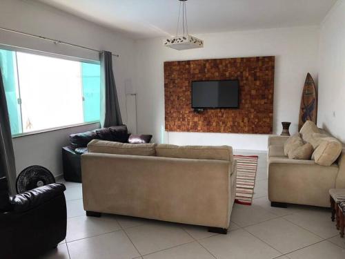 uma sala de estar com 2 sofás e uma televisão de ecrã plano em Pertinho da Praia Ar condicionado na Sala e em todos os Quartos - Venha curtir os Shows no Viva Verão Peruíbe em Peruíbe