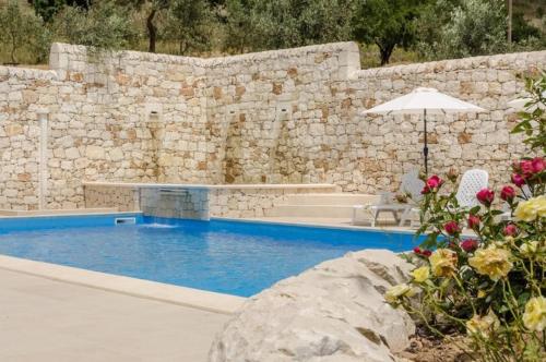a swimming pool with an umbrella and some flowers at Villa Dolce Valle in Ragusa