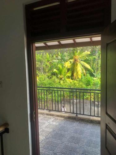 una puerta a un balcón con vistas a un bosque en Hesali villa, en Ambalangoda
