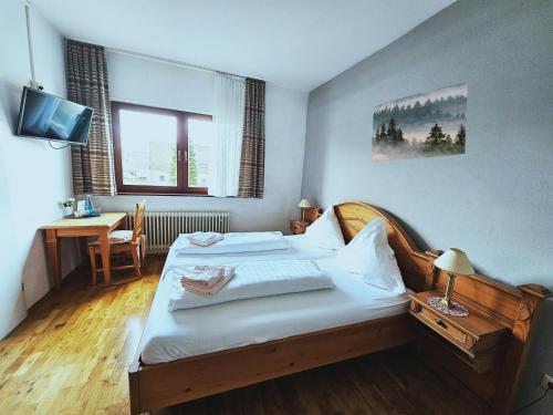 a bedroom with a bed and a desk and a television at Landgasthaus Sternen in Kehl am Rhein