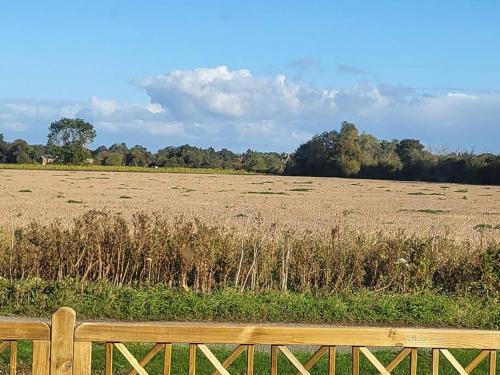 a wooden bench sitting in front of a field at Brooke View Barns No 1 in Norwich