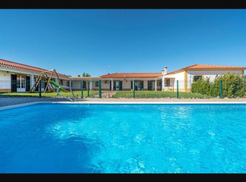 a large blue swimming pool in front of a house at O Cantinho dos Vieiras in Grândola