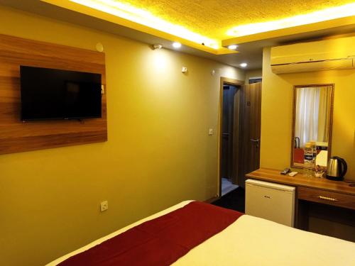 een slaapkamer met een bed en een flatscreen-tv bij Grand Marrakech Hotel in Yıldırım