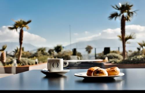 - une table avec deux assiettes de pâtisseries et une tasse de café dans l'établissement HO Ciudad de Jaén, à Jaén