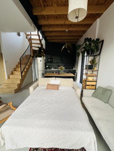 Cette chambre comprend un grand lit blanc et un canapé. dans l'établissement Le Resort, charmante petite villa d'architecte, à Saint-Jean-de-Védas