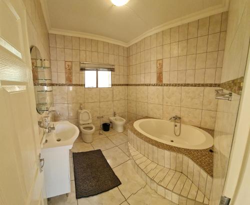 a bathroom with a tub and a toilet and a sink at Garden Oasis Cottage in Windhoek