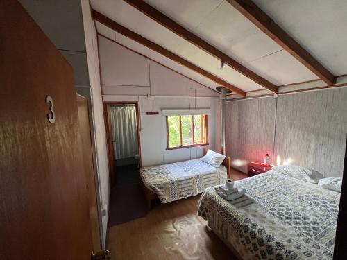 um pequeno quarto com 2 camas e uma janela em Hospedaje Los Angeles em Futaleufú