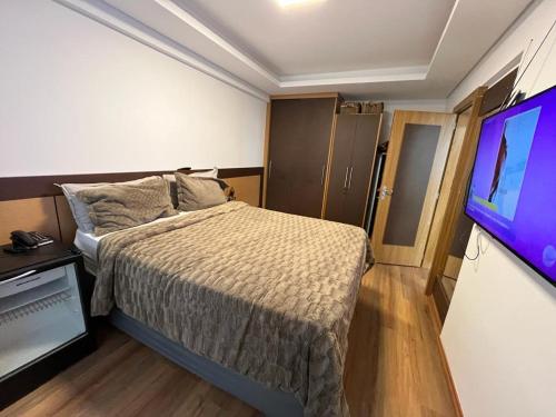 1 dormitorio con 1 cama y TV de pantalla plana en Central Park Flat Residence, en Florianópolis