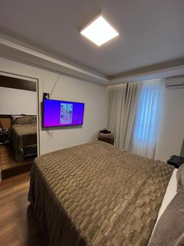 1 dormitorio con 1 cama grande y TV de pantalla plana en Central Park Flat Residence, en Florianópolis