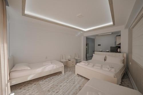 um quarto branco com 2 camas e um espelho em Hotel Angjelo em Borsh