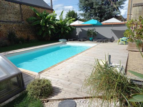a swimming pool with a wooden deck next to a house at Appartement, 2eme étage avec piscine partagée in Sedan