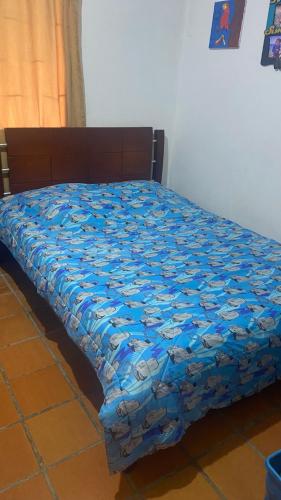 Una cama con un edredón azul encima. en Villa Pulguitos, en Los Santos