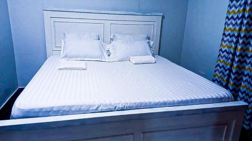 een blauwe slaapkamer met een bed met witte lakens en kussens bij One Bedroom at Bamburi in Mombasa