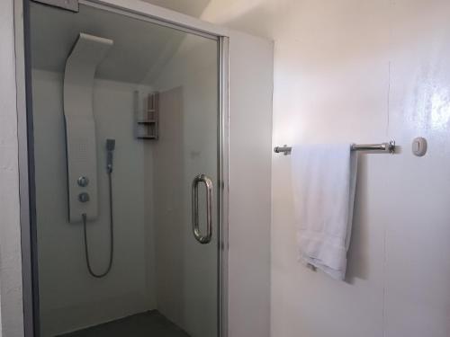 ducha con puerta de cristal y toalla blanca en Hanan Pacha Lodge en Puno