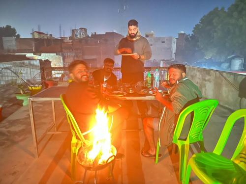 Un gruppo di uomini seduti intorno a un tavolo con un fuoco di Orchha Best Homestay a Orchha