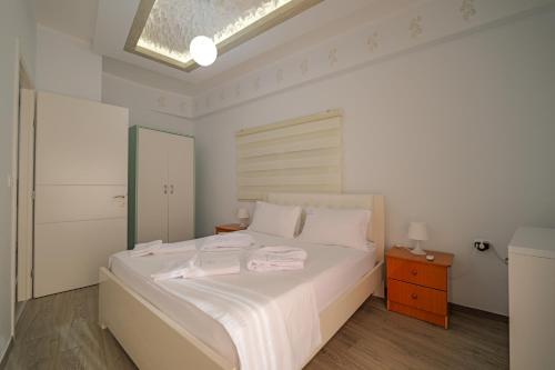 a white bedroom with a bed with two towels on it at Hotel Angjelo in Borsh