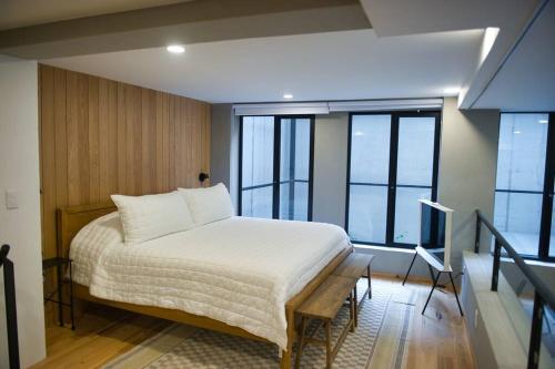 um quarto com uma cama com lençóis brancos e janelas em Roma Apartment with Private Terrace in CDMX em Cidade do México
