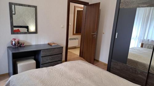 a bedroom with a bed and a desk with a mirror at Lusi Holiday, Смолянски езера in Smolyan