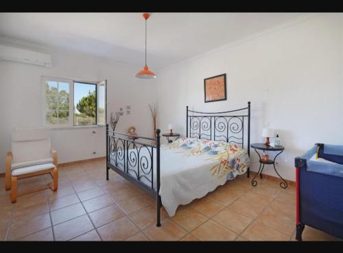 a bedroom with a bed and a chair at O Cantinho dos Vieiras in Grândola