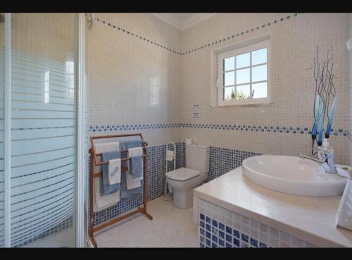 uma casa de banho com um lavatório, um WC e uma janela. em O Cantinho dos Vieiras em Grândola