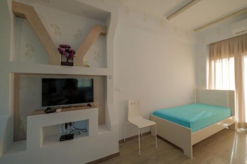 a living room with a tv and a chair at Hotel Angjelo in Borsh