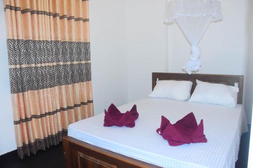 fedi viwe في اوداوالاوي: سرير أبيض مع وسادتين أرجوانيتين عليه