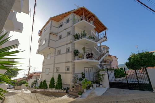 a tall white building with plants on the balconies at Hotel Angjelo in Borsh