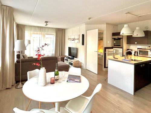 eine Küche und ein Wohnzimmer mit einem Tisch und Stühlen in der Unterkunft Luxe Duinsuite in Groet