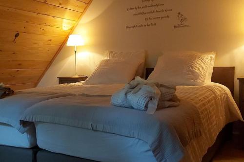1 dormitorio con 1 cama con sábanas y almohadas blancas en Tiny House Tholen, en Tholen