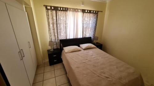 a bedroom with a bed with two pillows and a window at Serenity Retreat Cottage in Windhoek
