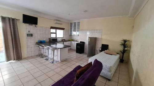 a large room with a kitchen and a bed in it at Serenity Retreat Cottage in Windhoek
