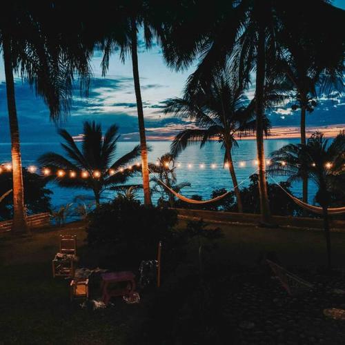 a view of a beach at night with palm trees at Casa Karina, Spectacular Ocean View Pool Oasis in Aticama