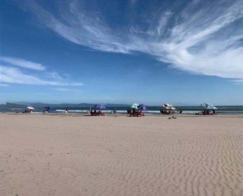 a group of people sitting on a beach with umbrellas at Casa Karina, Spectacular Ocean View Pool Oasis in Aticama