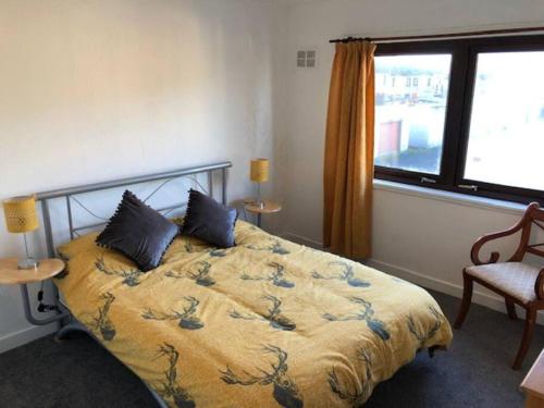 a bedroom with a bed with a yellow comforter and a window at Above the harbour wick in Wick