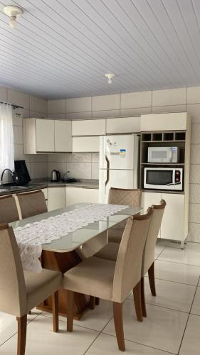 a kitchen with a table and chairs and a refrigerator at Casa praia da Gamboa garopaba in Garopaba