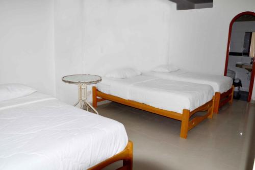 2 camas en una habitación con una mesa entre ellas en HOSPEDAJE LINDA LIRIO, en Paracas