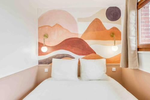 アティス・モンスにあるLe Boudoir, studio chic Aéroport d’Orlyの壁に絵が飾られた部屋にベッドが2つある