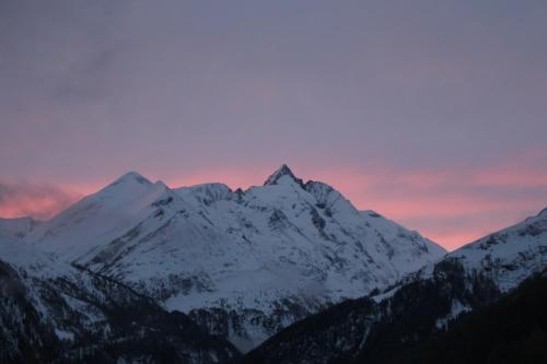 a snow covered mountain with a sunset in the background at Ferienhaus Gompitzer in Heiligenblut