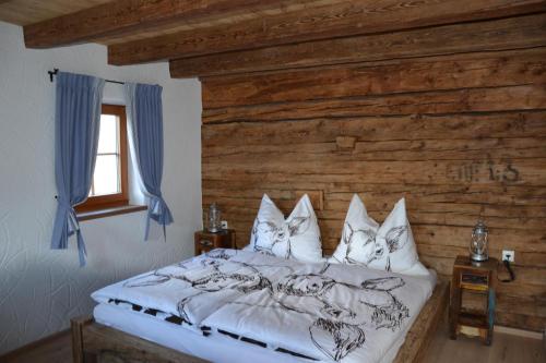 uma cama num quarto com uma parede de madeira em Ferienhaus Gompitzer em Heiligenblut