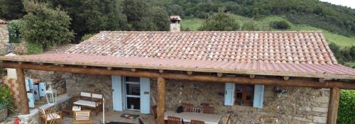 a stone house with a roof with a table and chairs at Stazzo Casa Bianco Fly in Aggius