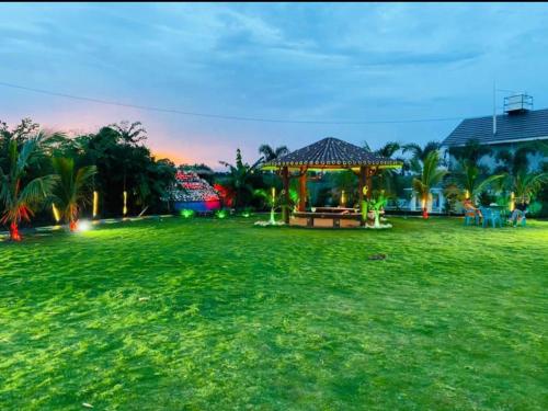 a grass field with a gazebo in a park at Leopard Farmhouse in Mhow