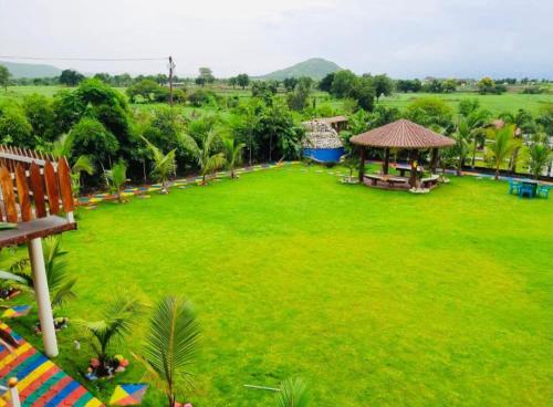 a large grassy field with a gazebo and a park at Leopard Farmhouse in Mhow