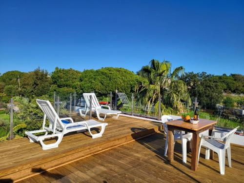three chairs and a table on a wooden deck at Casas Algarvias in Arroteia de Baixo