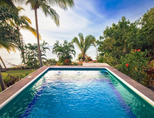 a pool with palm trees and the ocean in the background at Casa Karina, Spectacular Ocean View Pool Oasis in Aticama