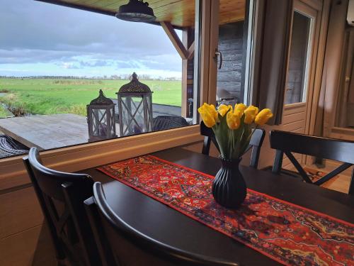 una mesa con un jarrón de flores amarillas. en Landelijk Tiny house in gemeente Edam/Volendam, en Middelie