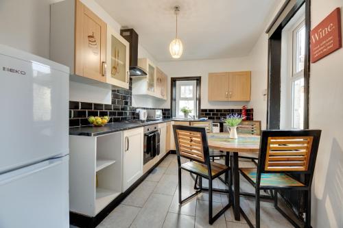 a kitchen with a table and chairs and a refrigerator at Newcastle CITY APT35,FREE STREET PARKING,4 BEDROOM HOUSE,8 SINGLE BEDS,FULL KITCHEN,ALL ROOMS WITH TVs,NETFLIX in Newcastle upon Tyne