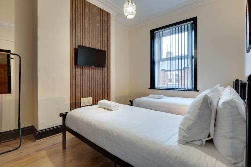 a hotel room with two beds and a flat screen tv at Newcastle CITY Apartments 35 in Newcastle upon Tyne