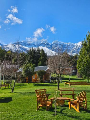 a group of benches in a field with mountains in the background at La Yaya - Villa Turismo in El Bolsón