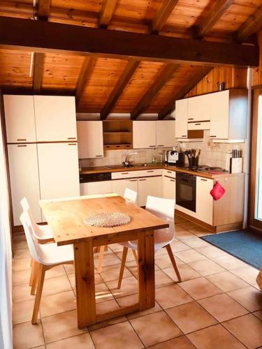 cocina con mesa de madera y electrodomésticos blancos en Chez Marilyne, en Savièse